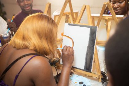 Grupo de adultos participa de uma aula de pintura e trabalha concentrado em projetos artísticos.