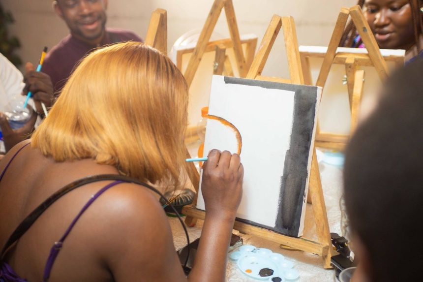 Grupo de adultos participa de uma aula de pintura e trabalha concentrado em projetos artísticos.