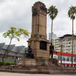 Monumento cercado por palmeiras e edifícios urbanos em Joinville, Santa Catarina