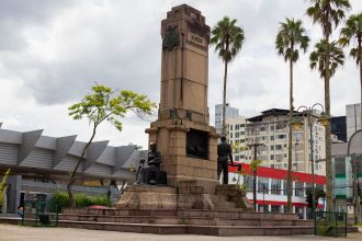 Monumento cercado por palmeiras e edifícios urbanos em Joinville, Santa Catarina